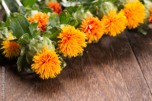 焦げ茶色のテーブルの上の紅花の花々のアップ