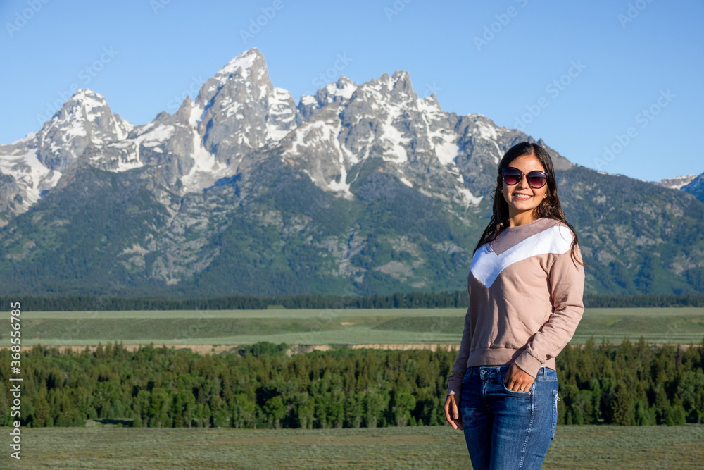 Portrait of young woman posing with a view of Grand Tetons in Wyoming, USA