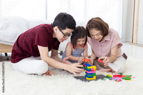 Disabled the kid and father, mother playing together with wooden toys.