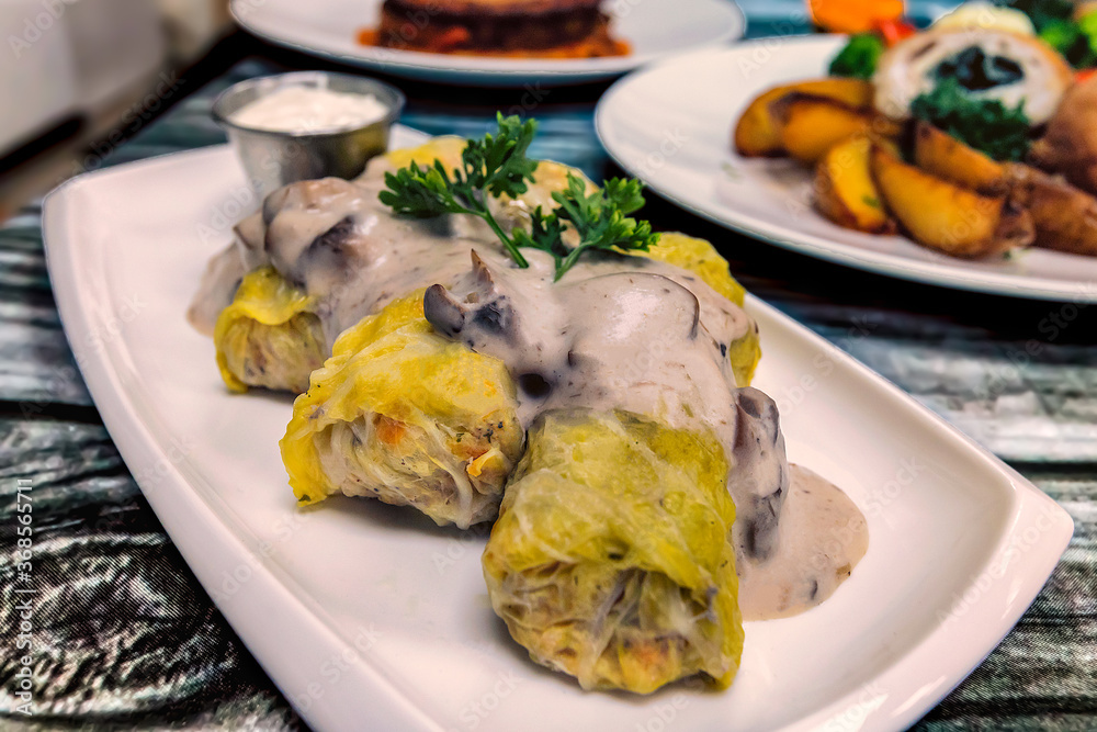 Close up of cabbage rolls on a plate with mushroom cream sauce over them.