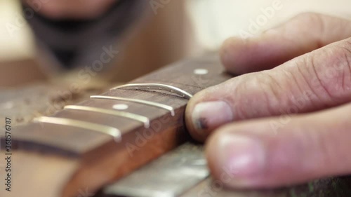 Craftsman artisan fitting in brass fret in wood guitar finger board arm slow motion