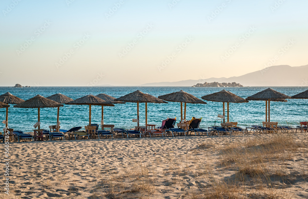 View of Plaka beach, with sunbeds and umbrellas, in the afternoon. Naxos island, Greece