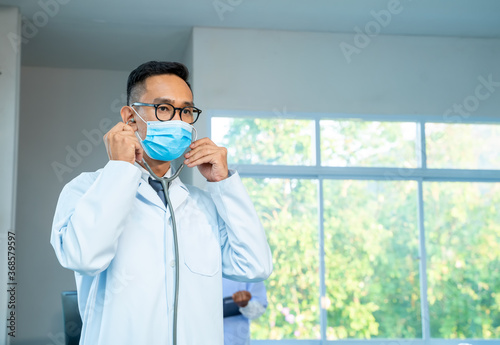 Doctor wearing protective mask to Protect Against Covid-19 standing with stethoscope at hospital,Healthcare and medicine concept.