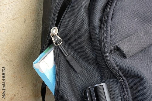 The black backpack with a damaged zipper cannot close the bag or keep the inside safe.