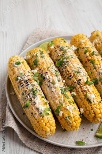 Homemade Elote Mexican Street Corn on a plate, side view.