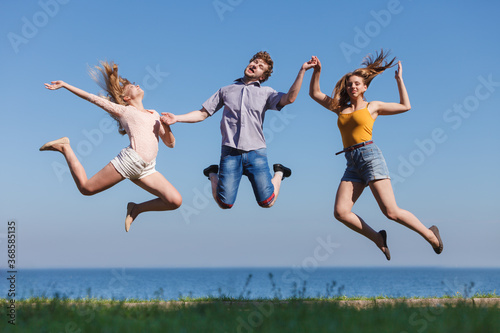 Carefree friends jumping by sea ocean water.