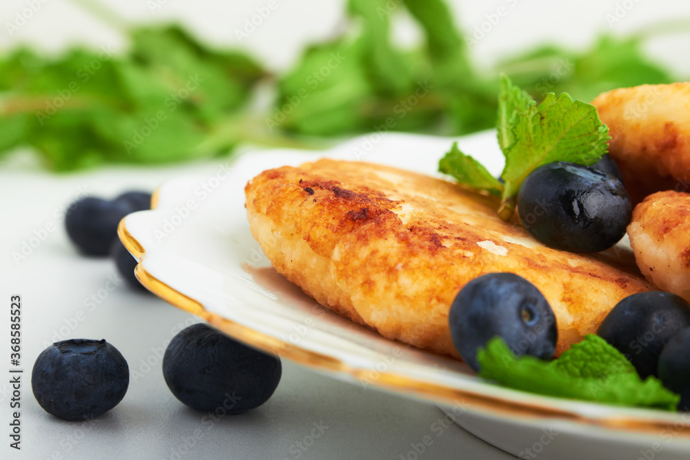 cottage cheese pancakes on a plate with blueberries and mint