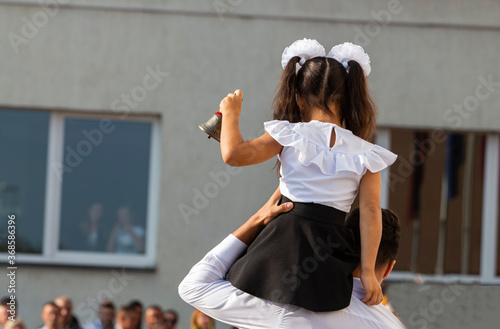 the girl on the boy's shoulder rings the bell on the first day of school, September 1