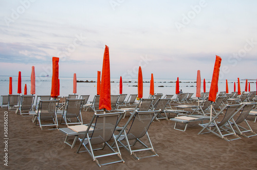 empty sunbeds red on the beach, closed due to covid-19 virus, pandemic