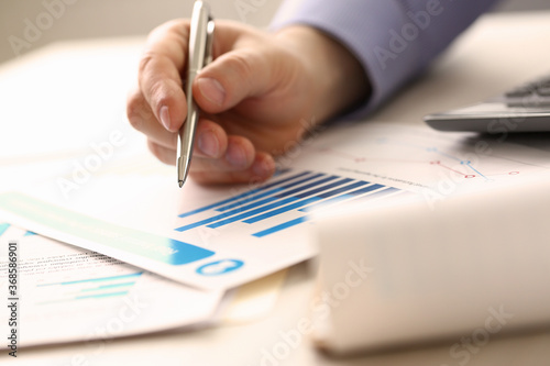 Businessman Controlling Prices Accounting Income. Man Hold Pen, Check Financial Data on Paper Chart, Blue Graph. Booker Analyzes Economy Earnings Using Calculator. Worker Salary Growth Calculation