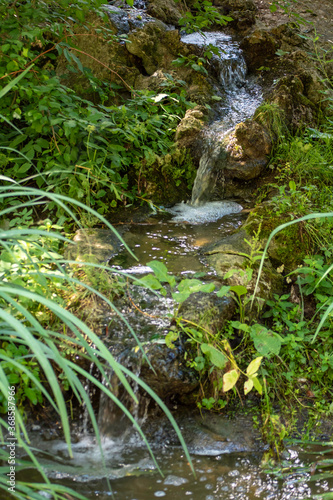 small river running on a stone way in the middle of the day sun