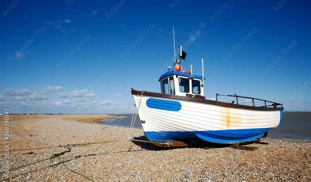 A working fishing boat on the shingle at Dungeness Beach in Kent. Famous for its iconic abandoned fishing boats, but there are still some that are sea worthy.