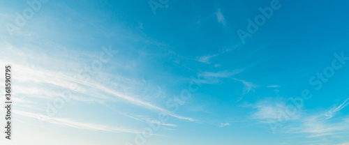 Background picture low angle of bright blue sky on a sunny day. There are fluffy white clouds and clear. Blue and white color contrast in soft tones. feeling fresh and relax. There is a copy space.