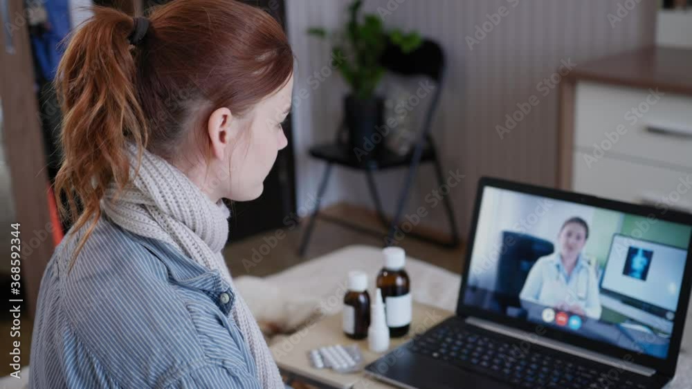telemedicine, patient with ill health communicates with a doctor online using video call and webcam on laptop isolating carnine from coronavirus while sitting on bed in room telemedicine, patient with ill health communicates with a doctor online using video call and webcam on laptop isolating carnine from coronavirus while sitting on bed in room