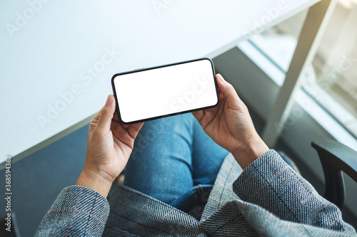 Top view mockup image of a woman holding mobile phone with blank white desktop screen © Farknot Architect