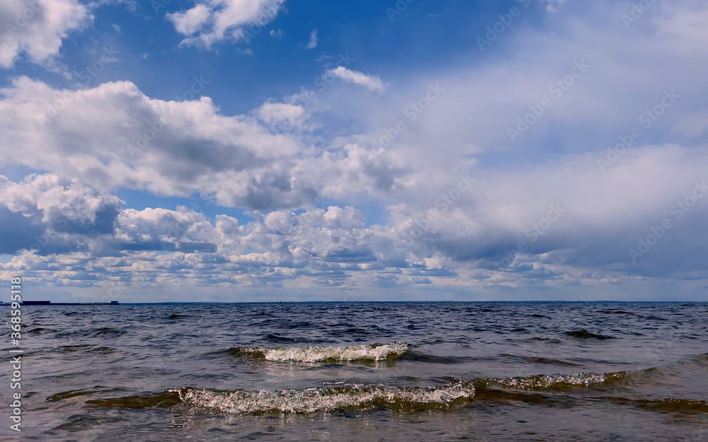 Beautiful blue sea with small waves and a blue sky with white clouds.