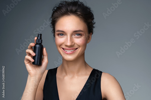 Woman with finishing spray. Photo of woman with perfect makeup on gray background. Beauty concept