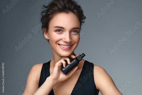 Woman with finishing spray. Photo of woman with perfect makeup on gray background. Beauty concept