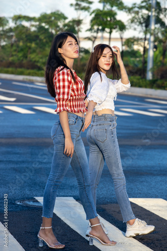 Two girls in jeans are taking pictures in the street © Mulin