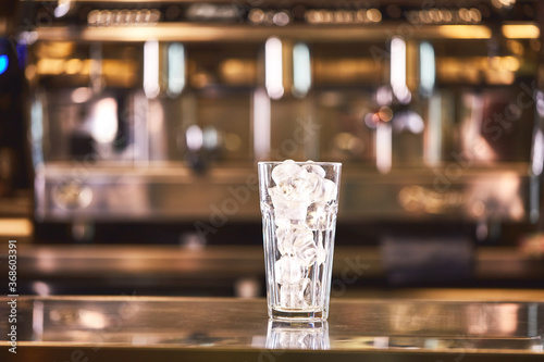 Glass of ice on coffee shop background