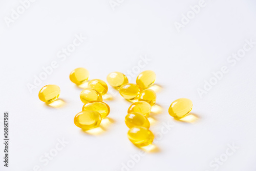 Selective focus of yellow fish oil supplement capsule on isolate white background. Medicine and vitamin for good body nutrition. Healthcare and medical concept.
