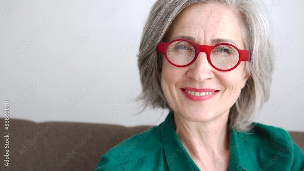 Grey-haired woman in fashionable glasses smiling to camera, femininity, trends Grey-haired woman in fashionable glasses smiling to camera, femininity, trends