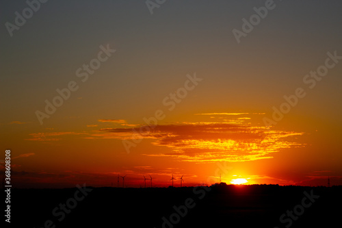 Sunrise with silhouettes of wind turbines on the horizon