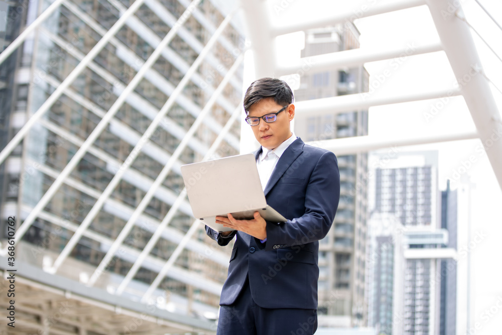 Fototapeta premium young businessman with laptop standing at outdoor.