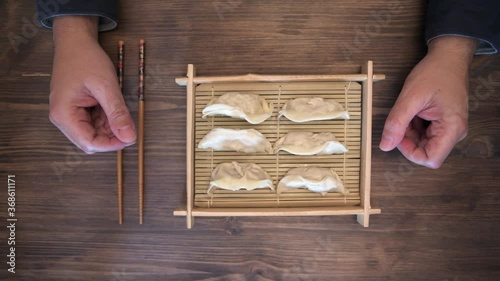 hands of a man with chopsticks ready to eat gyozas