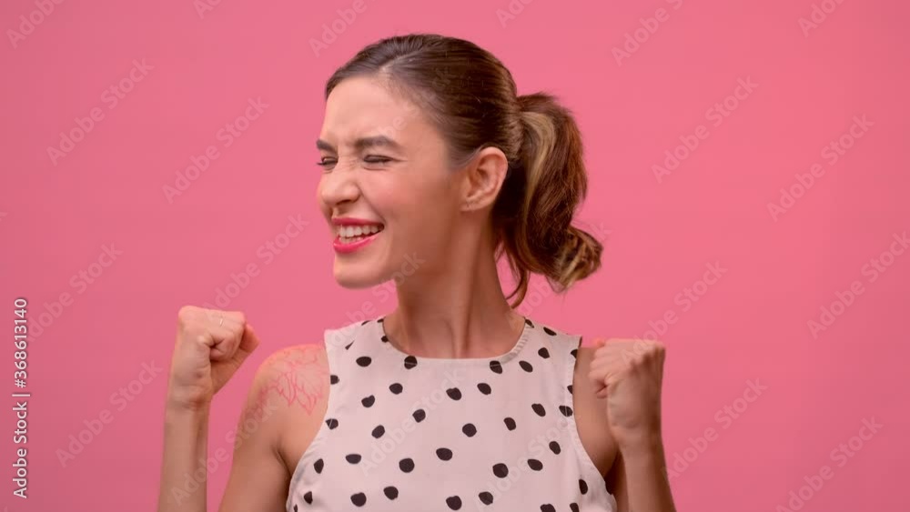 Caucasian pretty young woman has achieved her dream goal and is very happy to have fun on the background of a pink wall. Concept of victory and achievement of goals, positive emotions, feelings Caucasian pretty young woman has achieved her dream goal and is very happy to have fun on the background of a pink wall. Concept of victory and achievement of goals, positive emotions, feelings
