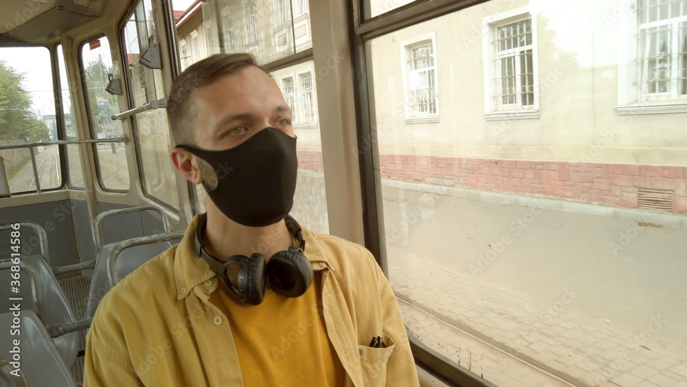 Man wearing a protective mask rides a tram and maintains a social distance. Preventing coronavirus during quarantine Man wearing a protective mask rides a tram and maintains a social distance. Preventing coronavirus during quarantine