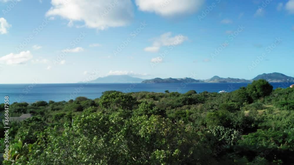 Drone camera captures the tops of dense forest and view of blue sea and mountains in Saint Kitts and Nevis Drone camera captures the tops of dense forest and view of blue sea and mountains in Saint Kitts and Nevis