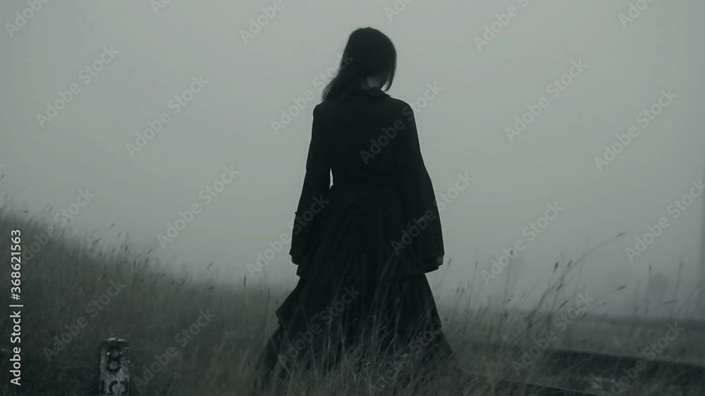 Horror scene of a mysterious scary woman in black dress into deep fog
