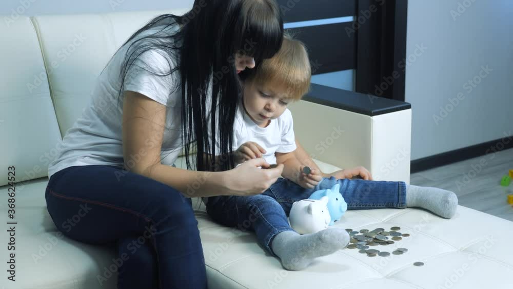 happy family little girl and mother saving lifestyle money concept. kid daughter and mom put money in a piggy bank. child blond put coins in piggy bank happy family little girl and mother saving lifestyle money concept. kid daughter and mom put money in a piggy bank. child blond put coins in piggy bank
