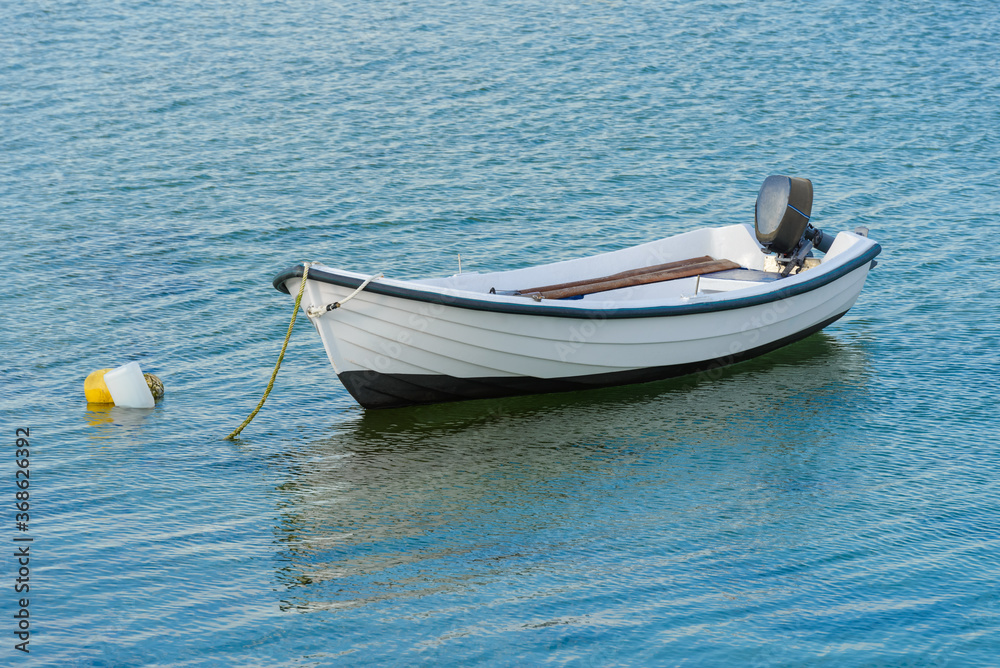 wooden fishing boat with a motor anchored in the sea, calm natural landscape