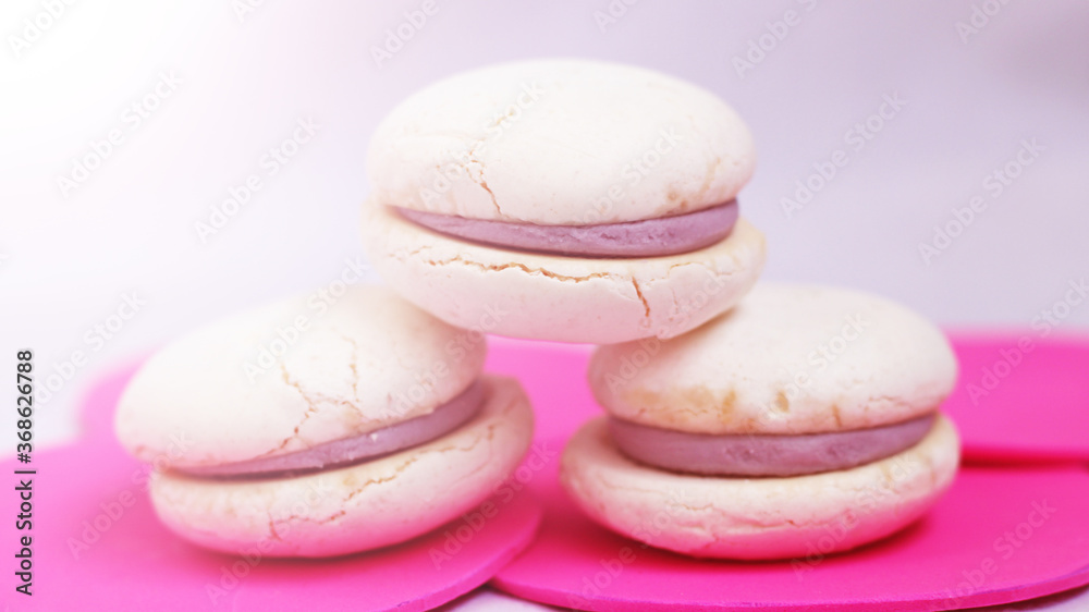 White macaroons with purple berry filling on pink background White macaroons with purple berry filling on pink background