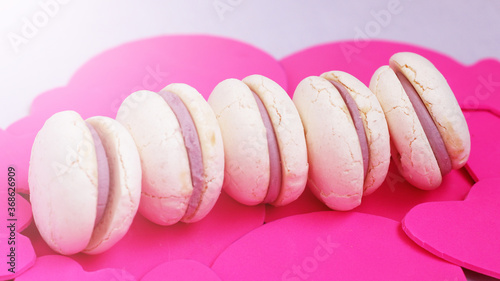 White macaroons with purple berry filling on pink background