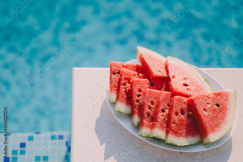 juicy watermelon sliced on plate with swimming pool background. summer vitamins berry.