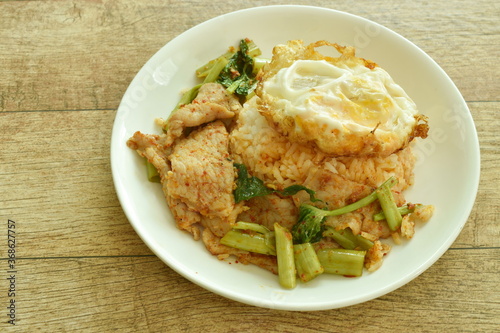 spicy fried fermenting pork slice in curry with topping crispy egg on rice egg in plate