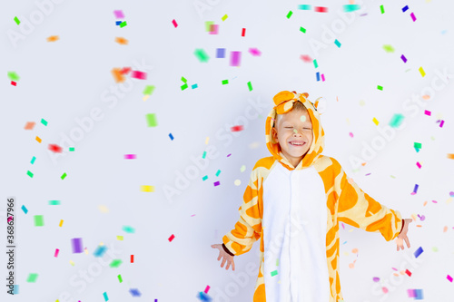 little boy in a fun bright giraffe costume on a white isolated background with confetti, children's birthday, place for text