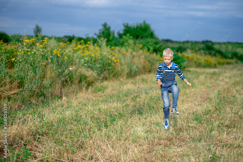 happy baby boy running across the field in summer, a child's lifestyle happy baby boy running across the field in summer, a child's lifestyle