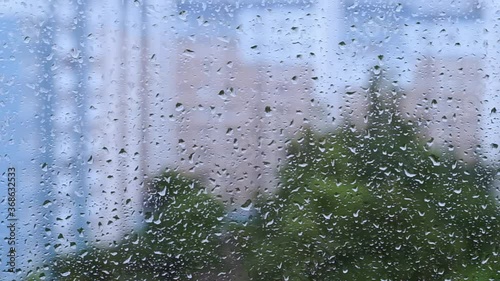 rainy droplets on a blue window glass transparent surface. drops on window shield in a rainy days in night city. stormy weather. isolation sad depression. rainy fall season. stay home.