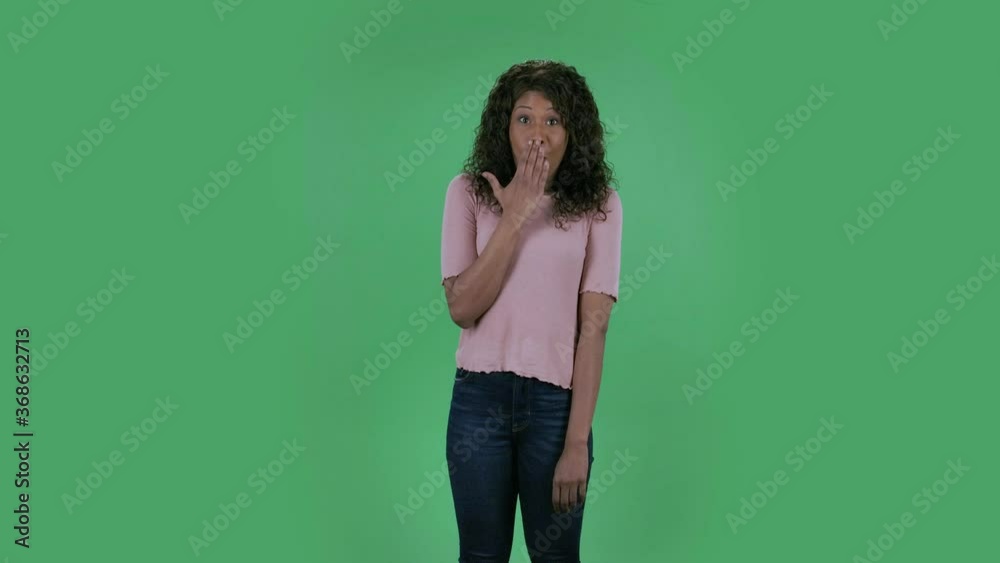 Portrait of beautiful african american young confused women is looking at camera saying oops and shrugging.Burning brunette with wavy hair in jeans and a beige blouse on a green screen in the studio. Portrait of beautiful african american young confused women is looking at camera saying oops and shrugging.Burning brunette with wavy hair in jeans and a beige blouse on a green screen in the studio.