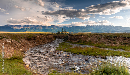 a river flowing through the Kurai steppe in Altai. Large mountain range with snow-capped peaks.