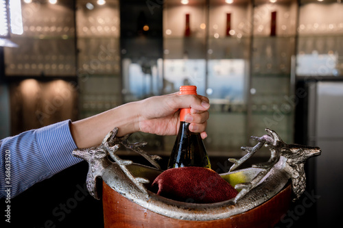 Hand holds Wine bottle in ice bucket. Wine bottle in bucket with ice. Champagne bottle in ice bucket 
