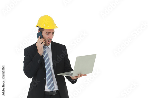 Handsome engineer in suit and white shirt and Wearing a yellow safety engineering hat with hand holding laptop and smartphone speaking and working in project isolated on White background.
