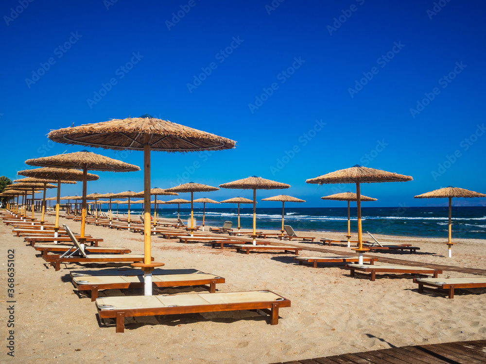 Empty deckchairs and parasols on empty beach