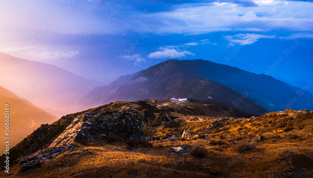 Colourful sunset behind hills. Soft lights are casted on the green grass. View from Lauribinayak in Gosainkunda trekking trail. It is a part of Langtang National park and Langtang trek. 