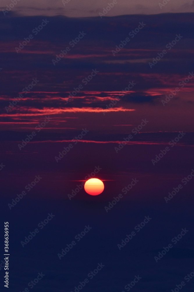 the pink solar disk seen from high altitude at sunrise. alpine sea at the mountain 