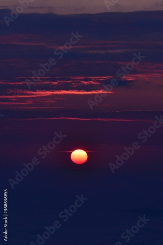 the pink solar disk seen from high altitude at sunrise. alpine sea at the mountain 